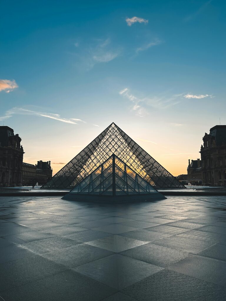 Stunning view of the Louvre Pyramid reflecting the sunset in Paris, France.